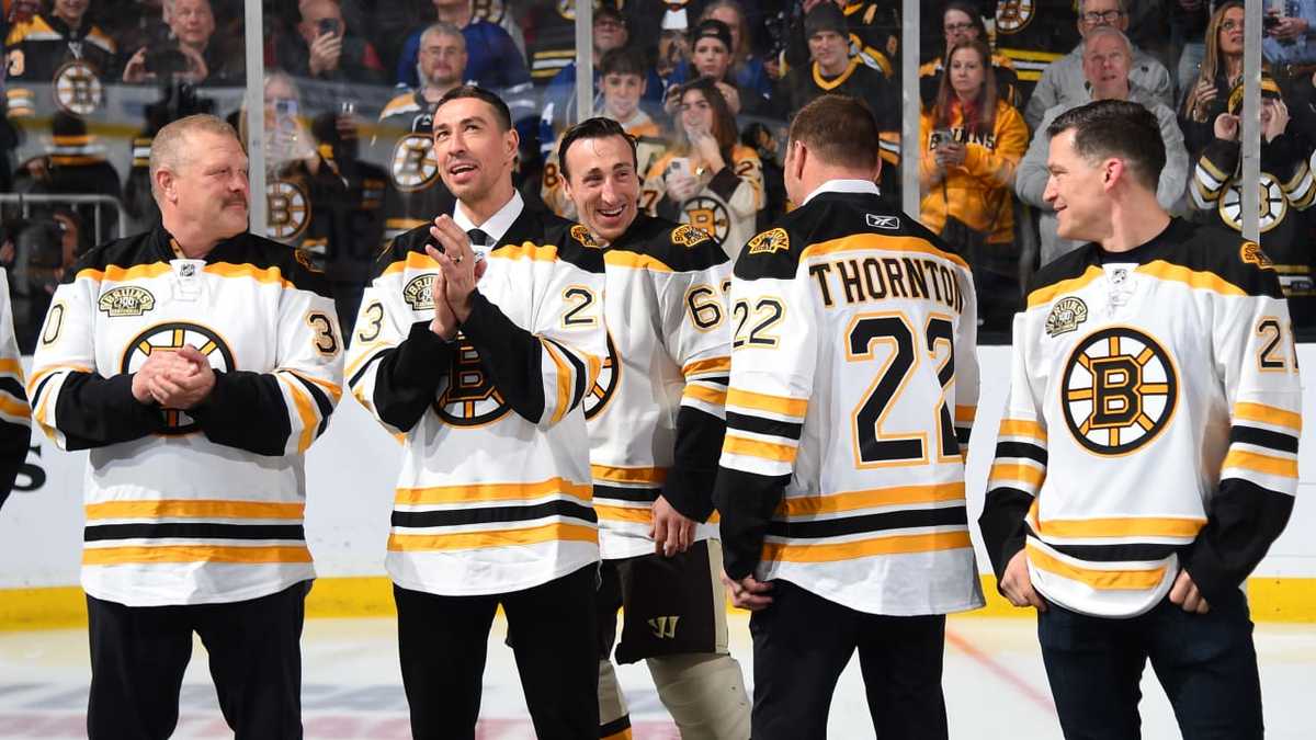 Boston Bruins players celebrating on the ice after winning a key playoff game, confetti falling and teammates embracing