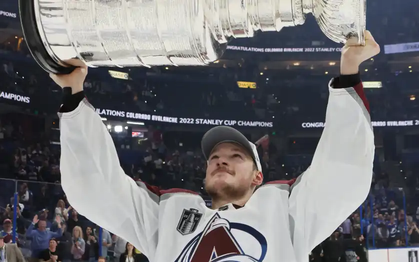Cale Makar raising the Stanley Cup in celebration with teammates during the victory ceremony