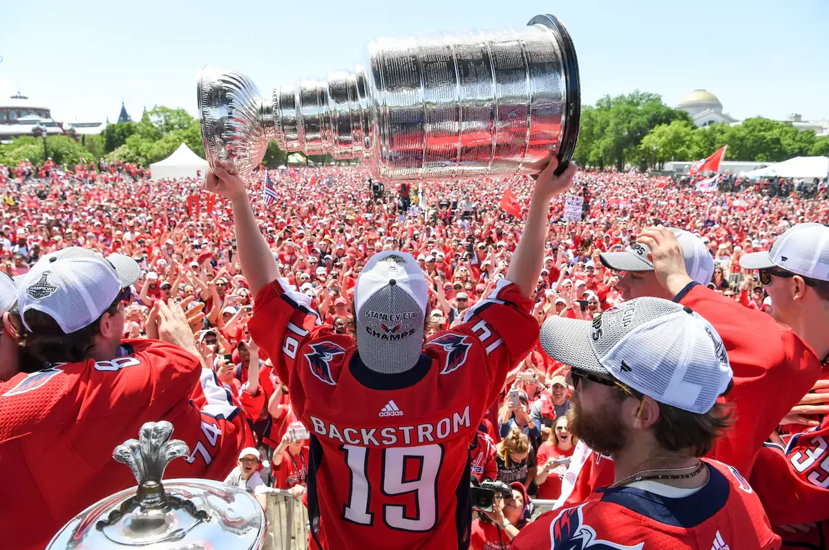 Alex Ovechkin lifting the Stanley Cup above his head with confetti falling around him