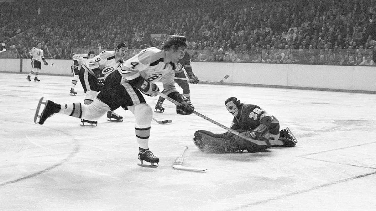 Bobby Orr skating hard behind his own net with the puck, showcasing speed and control