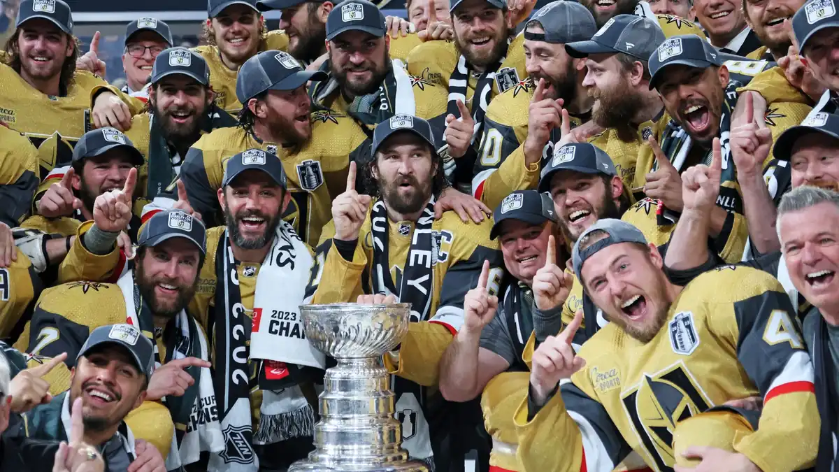 Vegas Golden Knights captain holding the Stanley Cup aloft amid confetti at the championship presentation