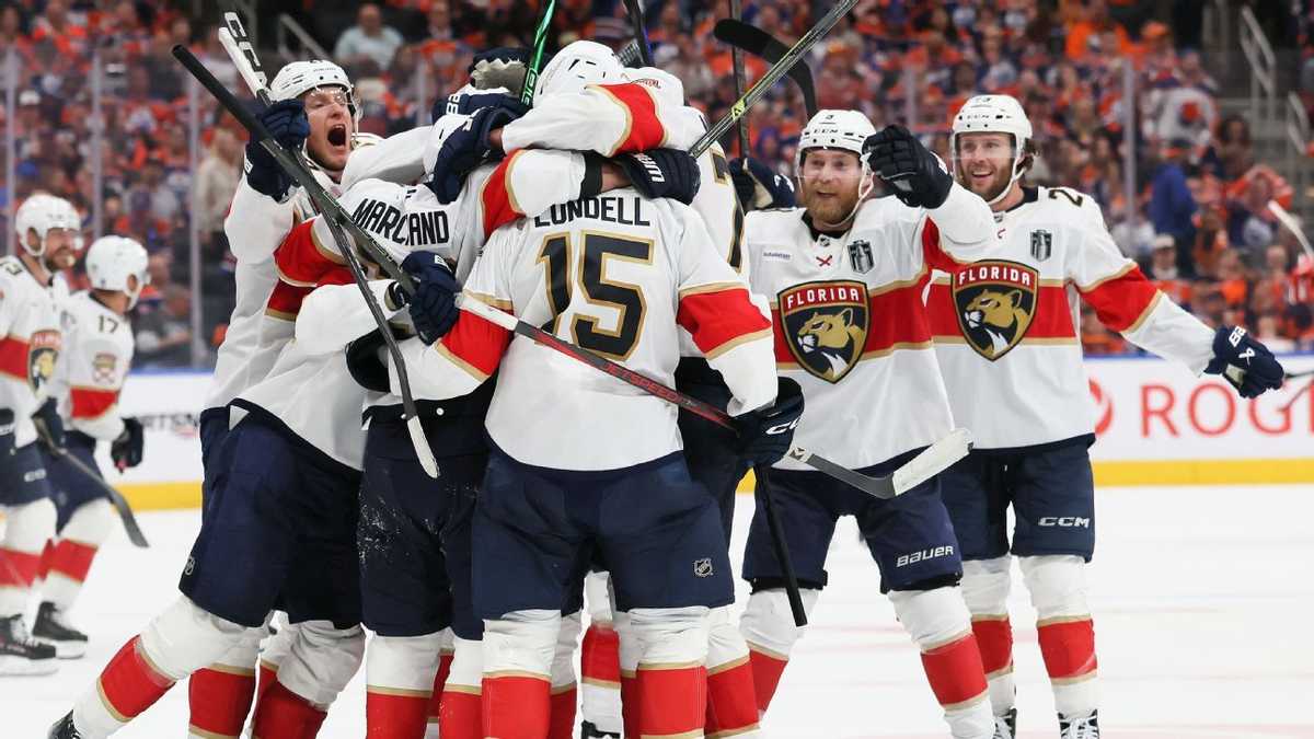 Hockey players embracing and raising sticks on the ice after a series-clinching goal, confetti in the arena